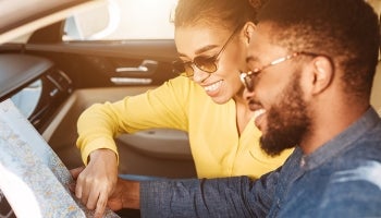 Couple sitting in a car with a map planning a summer road trip.
