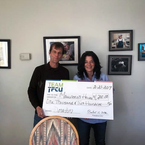Two Teachers employees holding a Maureens Haven donation check