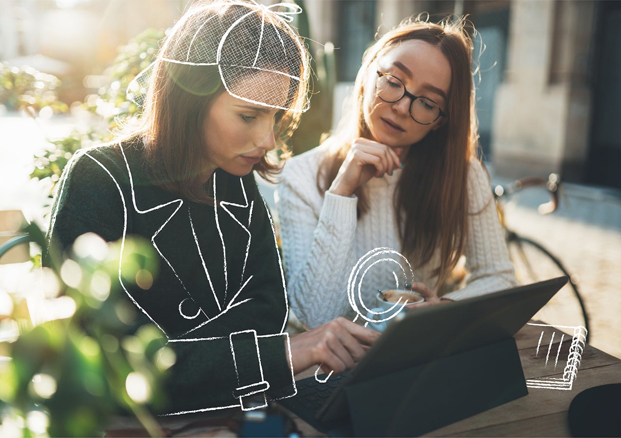 two women on patio using laptop