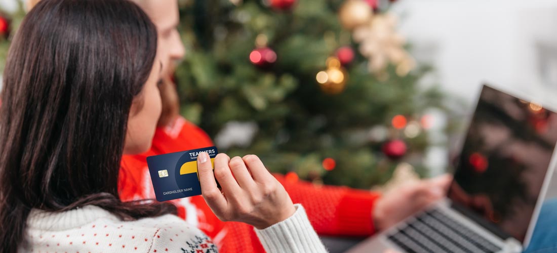 woman holding credit card while looking at laptop