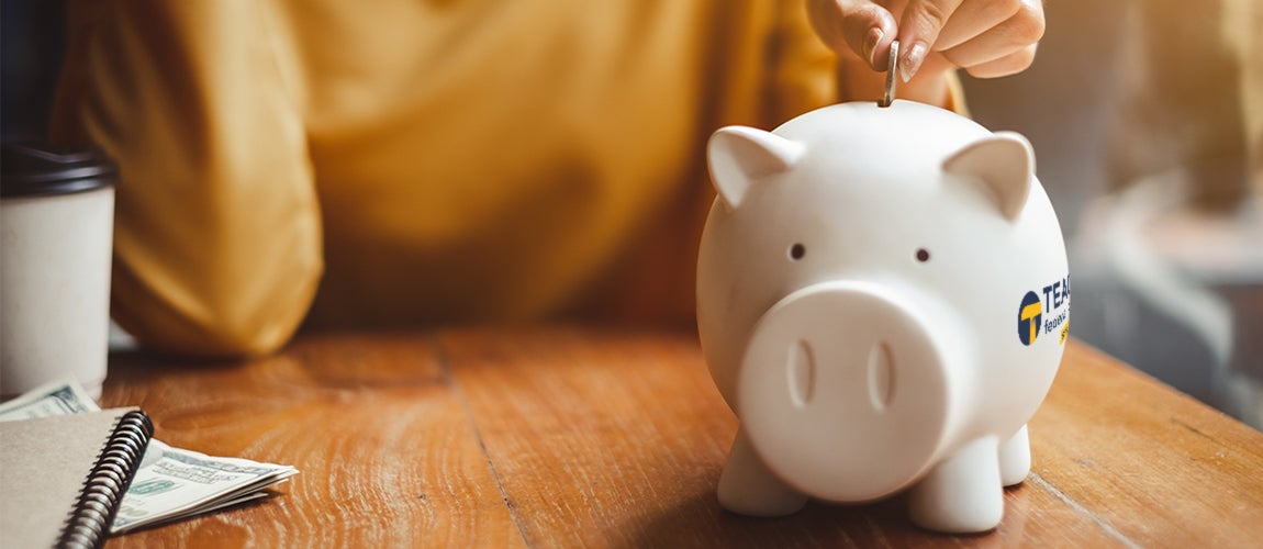 Woman putting a coin in a Teachers Federal Credit Union piggy bank