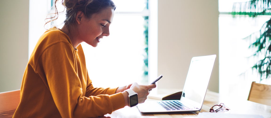 College student using cell phone and computer to examine student loans