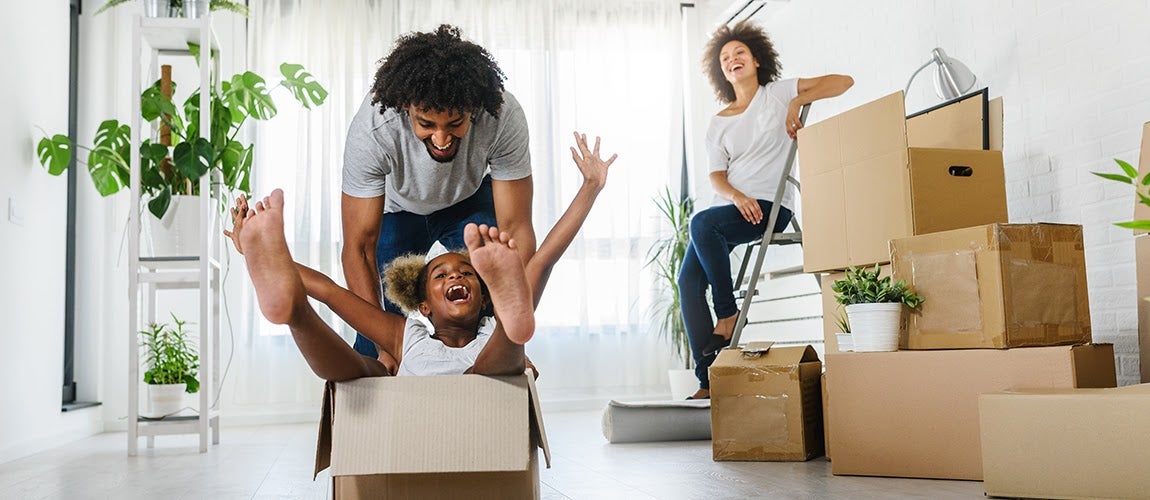 A young family with a mother, father and child who just moved into a new house with moving boxes.