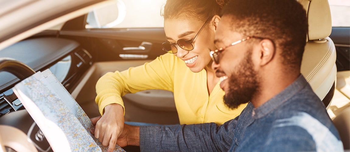 Couple sitting in a car with a map planning a summer road trip.