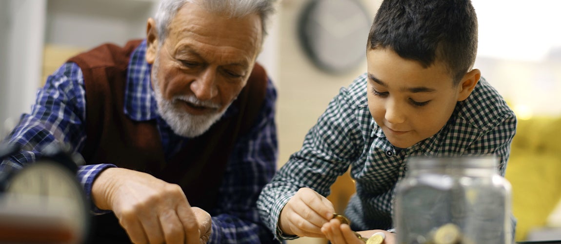 Grandfather teaching grandson how to manage finances by counting coins.