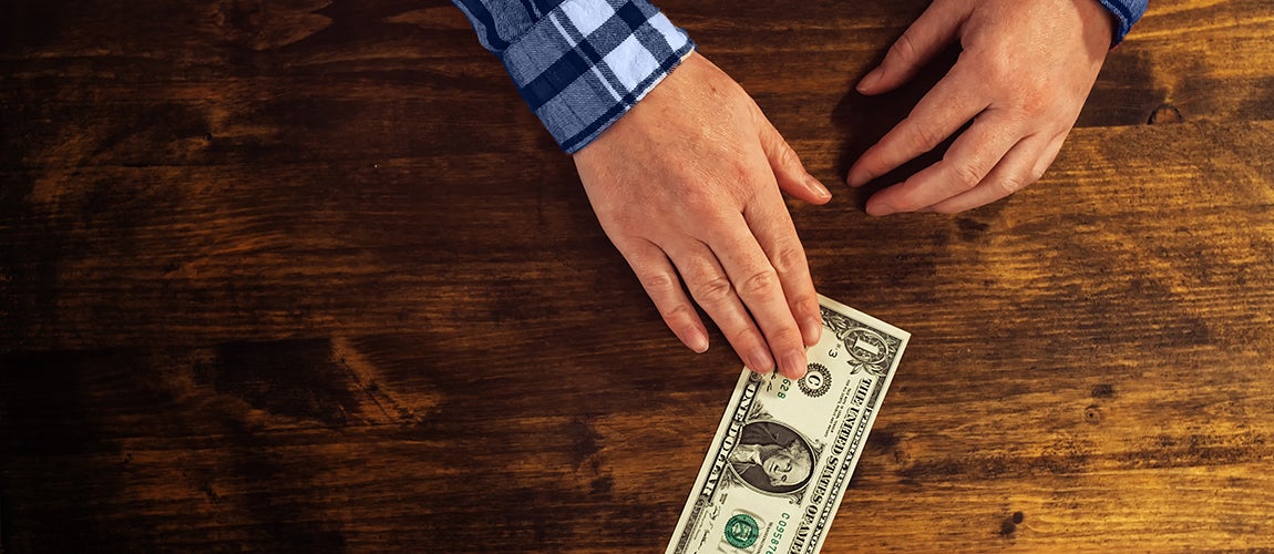 Man placing dollar on table.