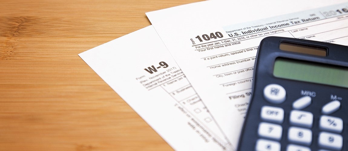  A calculator, W-9 and 1040 tax forms on top of a desk.