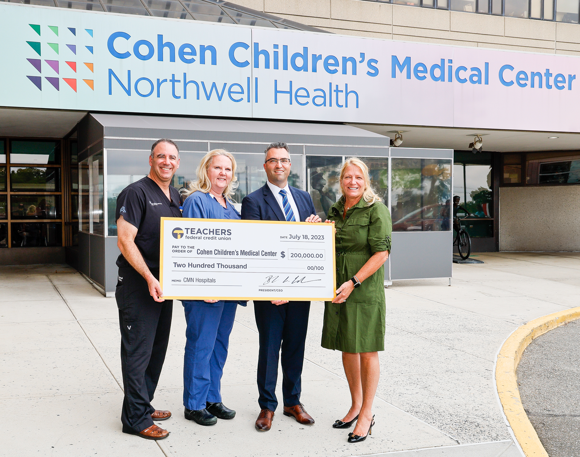 Cohens and Teachers in front of Building with Check