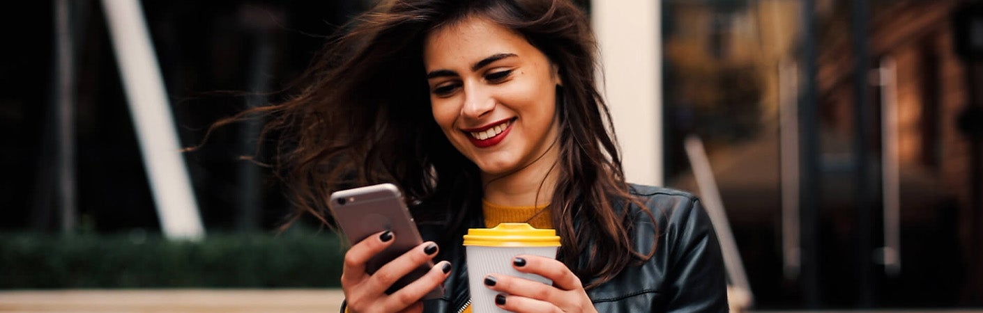 Woman looking at phone and drinking coffee