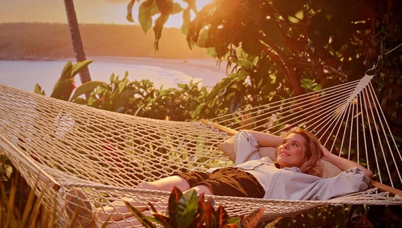 Teachers customer relaxes in hammock with sunset view