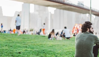 man sitting in a park beneath the Brooklyn Bridge