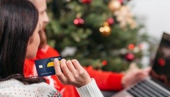 woman holding credit card while looking at laptop