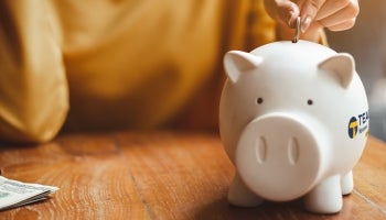 Woman putting a coin in a Teachers Federal Credit Union piggy bank