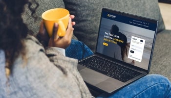 Woman holding yellow mug with a laptop open to the Teachers Federal Credit Union website