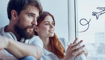 Couple sitting next to a window contemplating travel