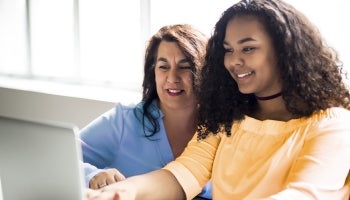 Mother and daughter looking at a laptop and learning how to invest.