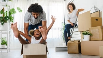 A young family with a mother, father and child who just moved into a new house with moving boxes.