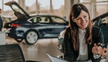 Woman inside a car dealership negotiating a car loan.