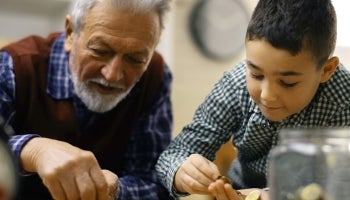 Grandfather teaching grandson how to manage finances by counting coins.