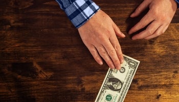 Man placing dollar on table.