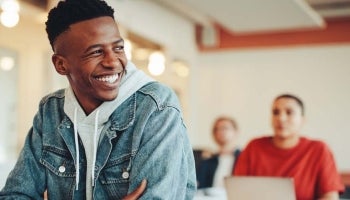  Male student sitting in a classroom considering student loans and learning how to refinance student loans.