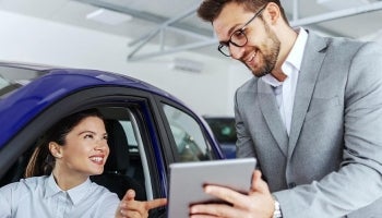 Young woman at car dealership talking to a salesperson about financing a new car
