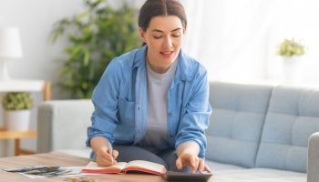 A woman uses a calculator to track her expenses and debt.