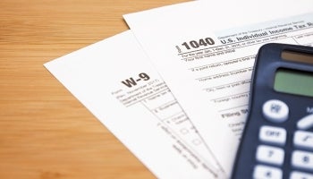  A calculator, W-9 and 1040 tax forms on top of a desk.