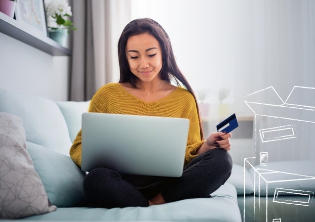 woman using computer while holding credit card