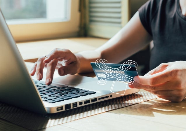 Man typing on computer with secure credit card in hand