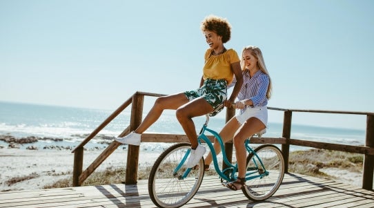 two girls riding bike near ocean