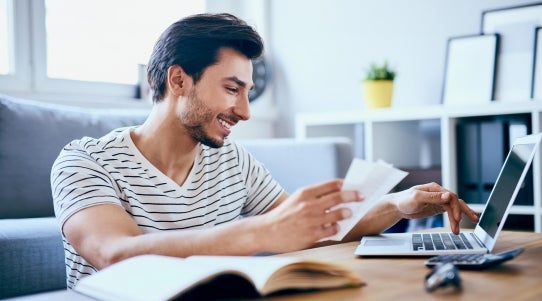 man looking at his computer with receipts in hand