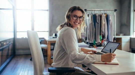 woman sitting at desk writing on a notepad