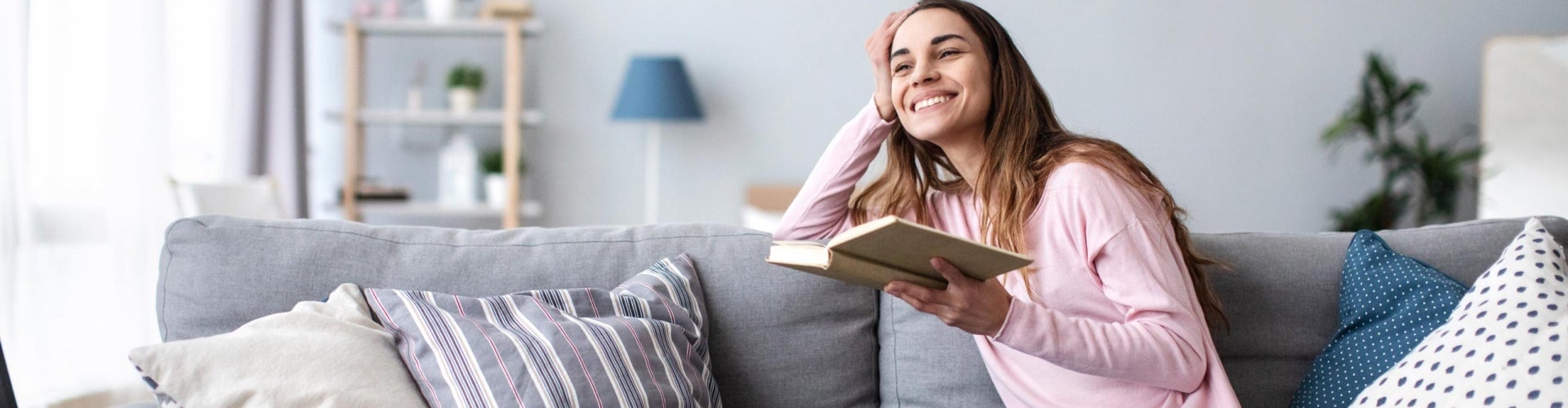 woman smiling while reading book on couch